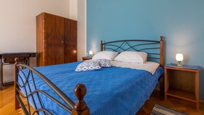 A neatly made bed with a blue blanket, wooden headboard, and two bedside lamps.