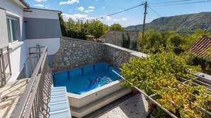 A private pool with stone walls, a balcony, and a view of a mountainous landscape.