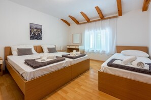 A hotel room with two wooden beds, white linens, and a wooden ceiling with exposed beams.