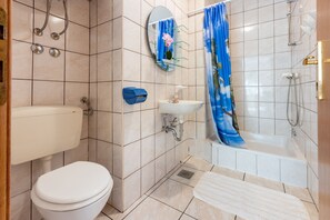 A bathroom with a toilet, sink, shower, and a blue shower curtain.
