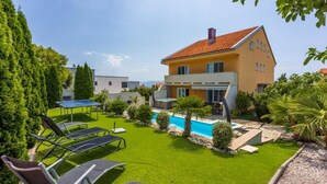 A modern two-story house with a swimming pool, green lawn, and outdoor furniture. - House Moderna 2 (Crikvenica)