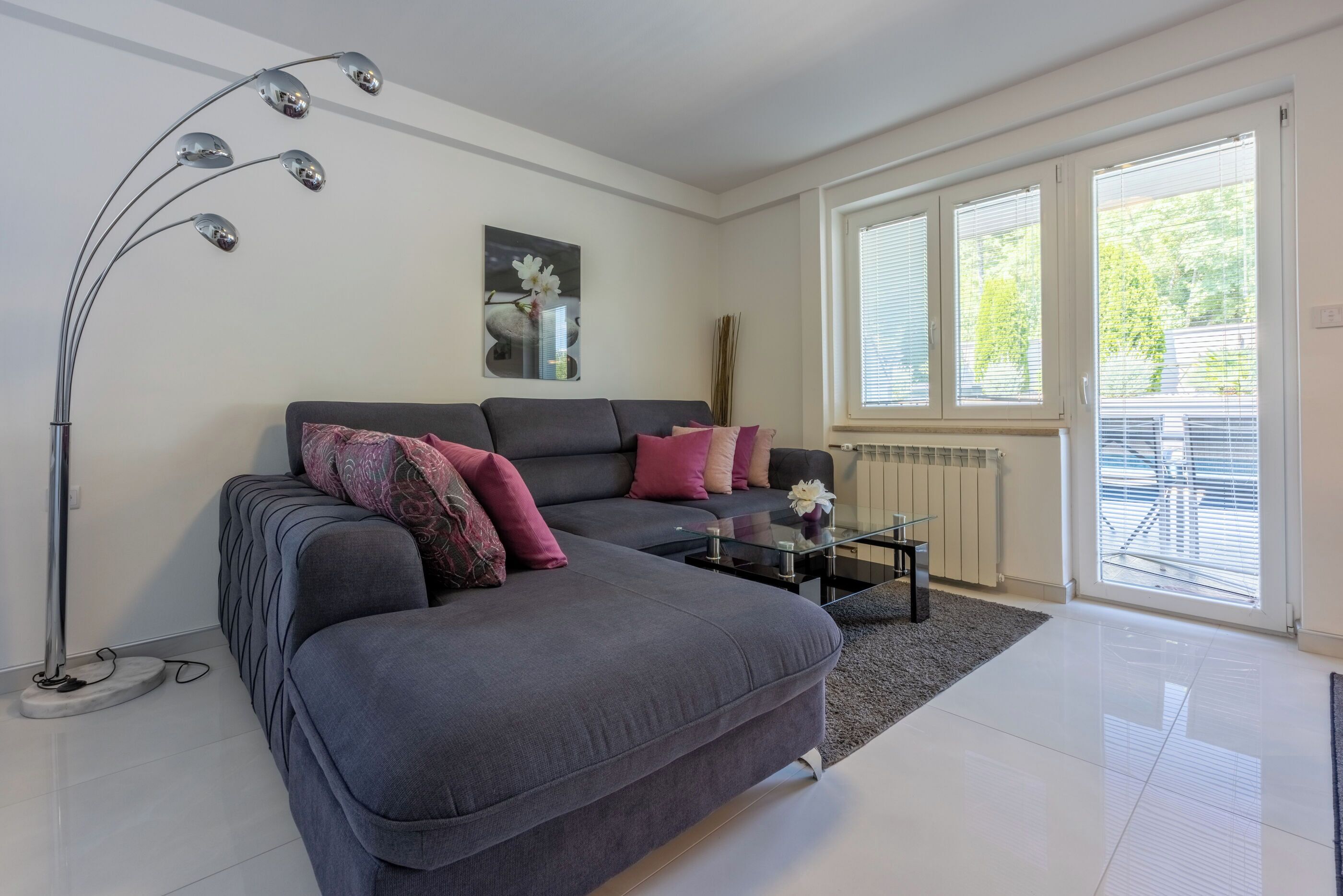 A modern living room with a grey sofa, a glass coffee table, and a floor lamp.