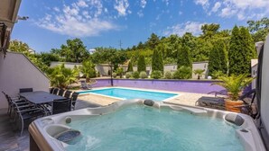 A hot tub with a pool, outdoor seating, and lush greenery. - House Moderna 2 (Crikvenica)