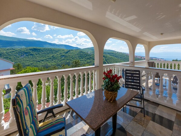Ein Balkon mit Tisch, Stühlen und einem Blumenstrauß.
