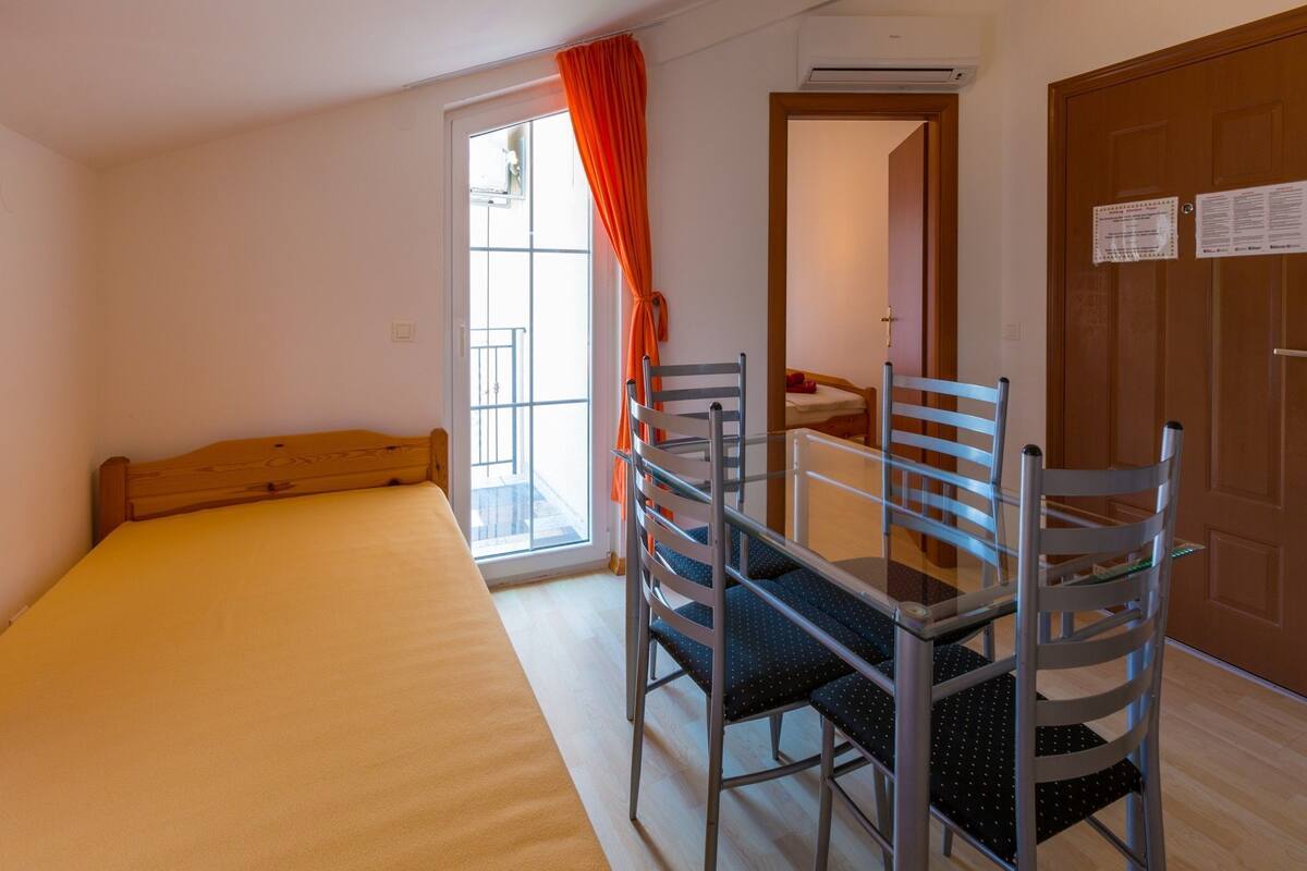 Eine kleine, einfache Unterkunft mit einem Bett, einem Tisch und zwei Stühlen.