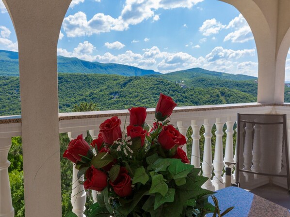 A balcony with a view of green mountains and a clear sky.