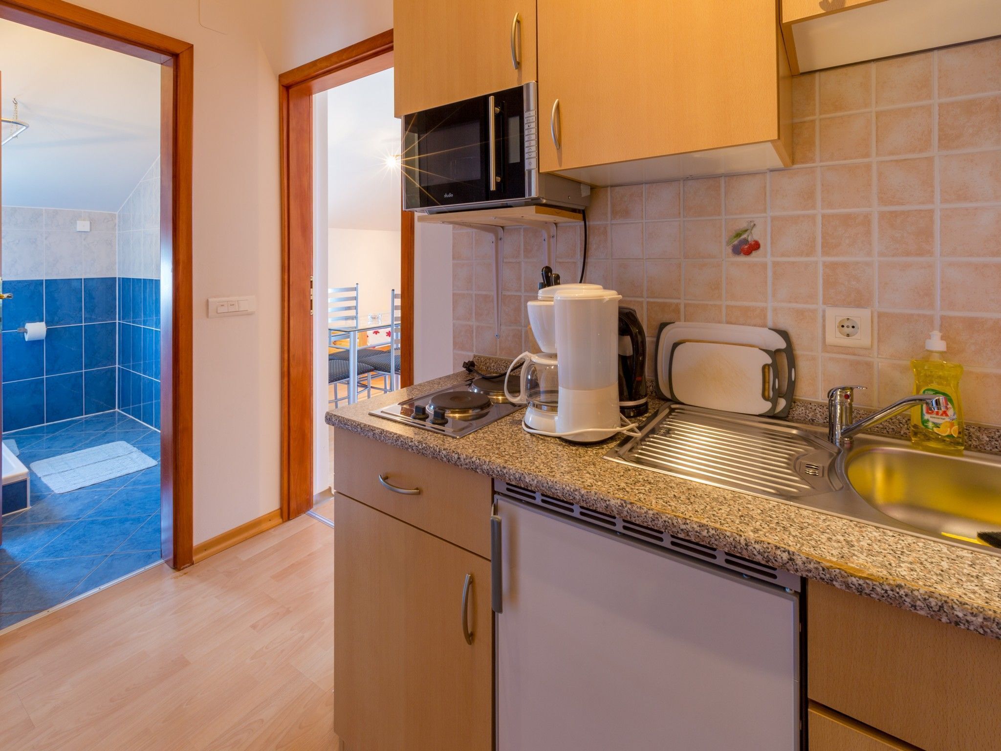A compact kitchen with a microwave, coffee maker, and sink.