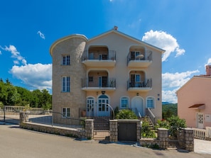 Ein mehrstöckiges Gebäude mit Balkonen, einer Steinfassade und blauem Himmel.