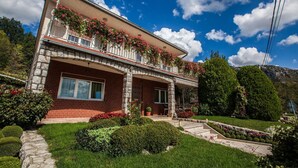 Une maison à deux étages dotée d’un balcon orné de fleurs, d’un chemin de pierre menant à l’entrée et d’un jardin bien entretenu.