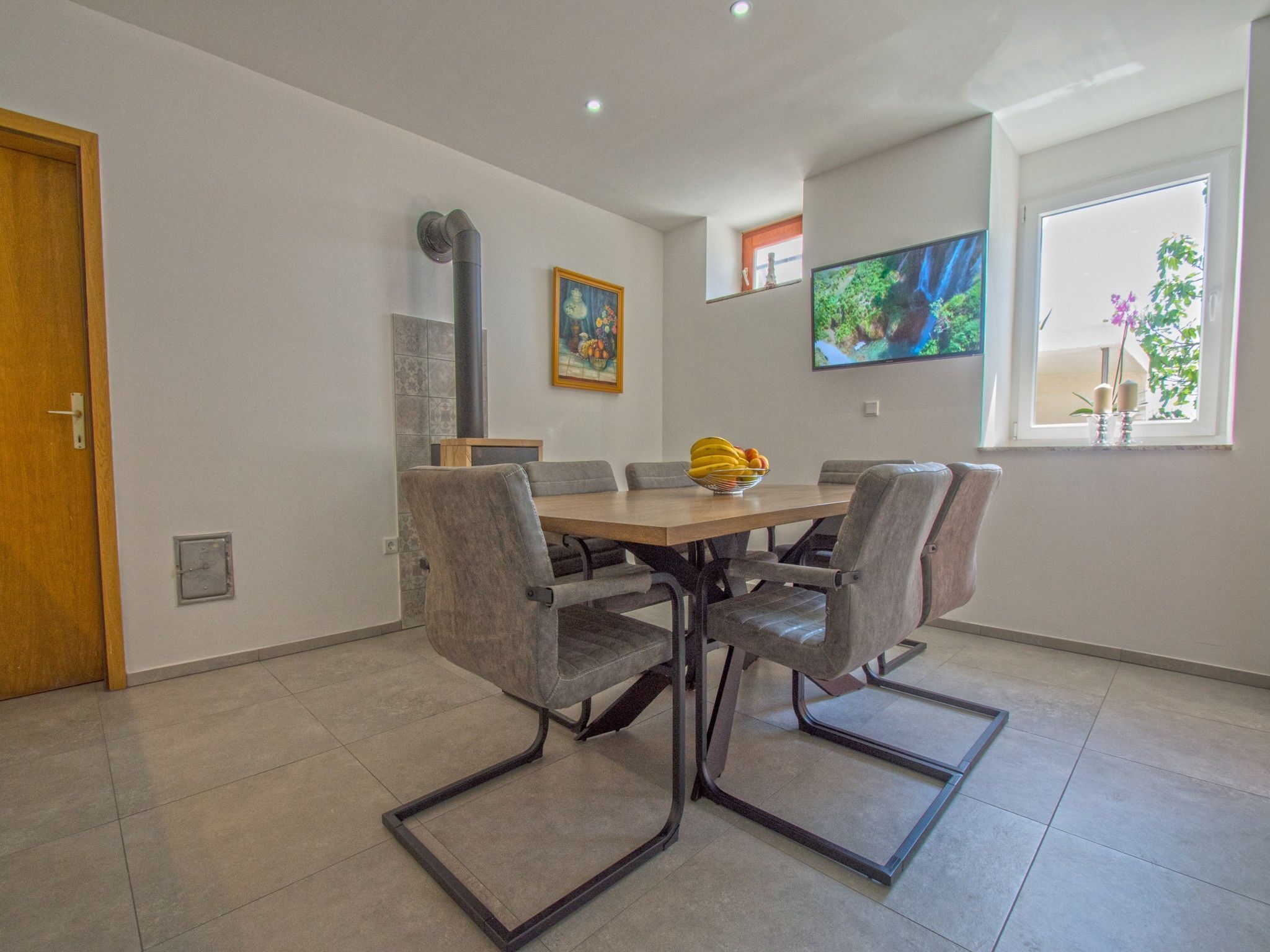 Un comedor con mesa de madera y sillas tapizadas en gris.