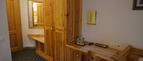 A room with wooden furniture, a mirror, a small table with bottles, and a power outlet.