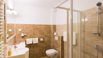 Une salle de bain moderne avec une douche à parois de verre, un lavabo avec un miroir et des toilettes.