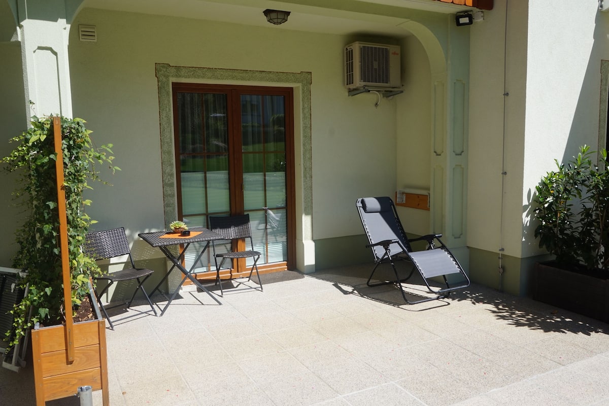 Un patio con dos sillas, una mesa y una planta pequeña.