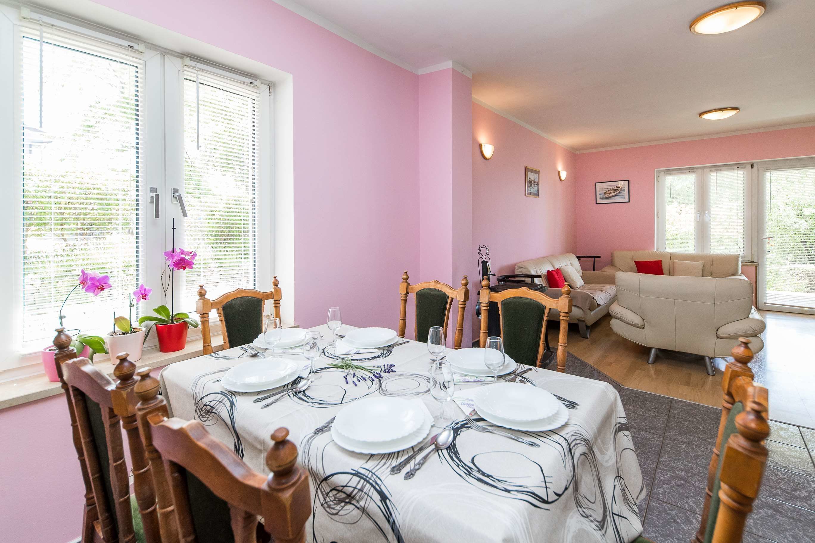 Zona pranzo con tavolo apparecchiato per quattro, circondato da sedie in legno.