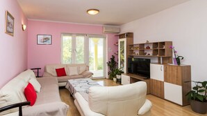 Una sala de estar con un sofá, un televisor y un mueble de madera.