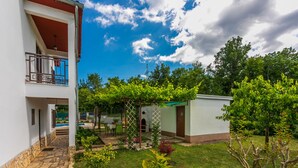 A two-story building with a stone pathway leading to a covered outdoor seating area. - House Marija (Labin)