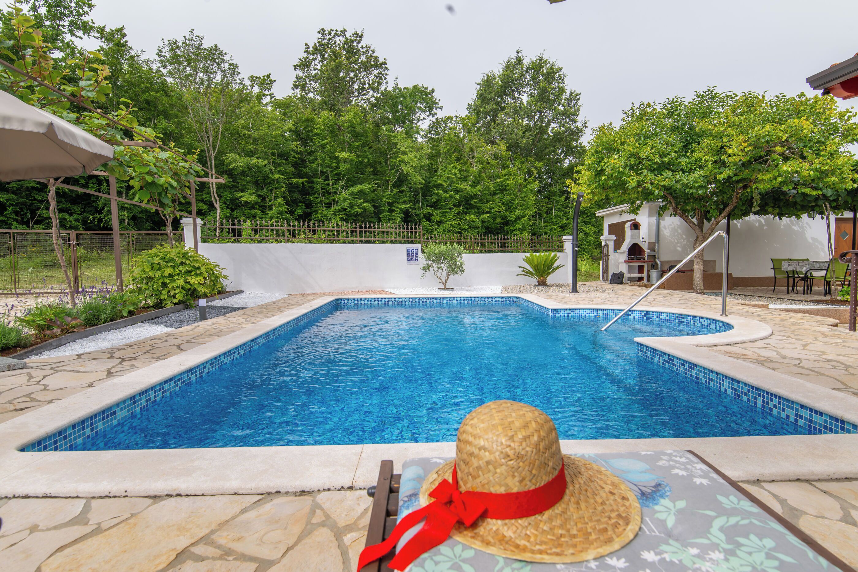 A swimming pool with a sun lounger and a straw hat.