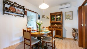 A dining area with a wooden table and chairs, a chandelier, and a cabinet with glass doors. - House Marija (Labin)
