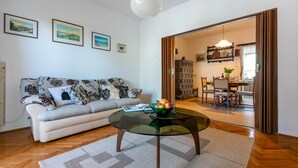 A living room with a sofa, a glass coffee table, and a dining area with a table and chairs. - House Marija (Labin)