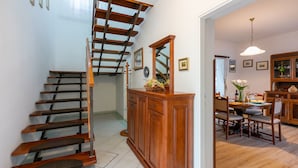 A staircase with wooden steps and a wooden railing, leading to a dining area with a table and chairs. - House Marija (Labin)