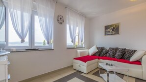 Ein modernes Wohnzimmer mit einem weißen Sofa, roten Wohndecken, einem Couchtisch und einem Bild an der Wand.