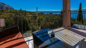 Ein Balkon mit einem Glastisch, einem Stuhl und einer Wasserflasche.