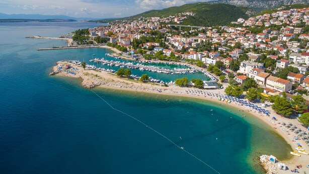 Eine Küstenstadt mit einem Yachthafen, Strand und Wohngebäuden.