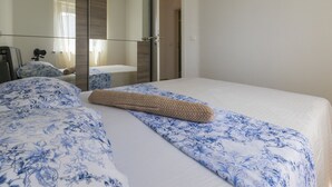 Ein Hotelzimmer mit einem großen Bett, einem Nachttisch, einem Spiegel und einem durch eine offene Tür einsehbaren Badezimmer.