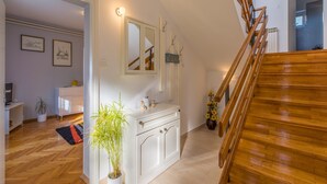 Ein geräumiger Wohnbereich mit einer Holztreppe, einem weißen Schrank und einem Blumentopf.