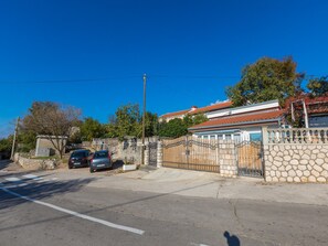 Un quartiere residenziale con un viale privato, auto parcheggiate e una casa con tetto in tegole.