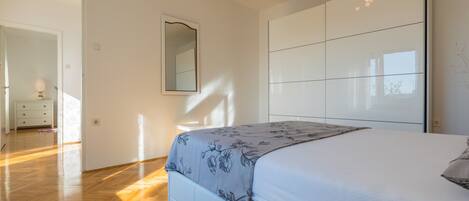A bedroom with a bed, a dresser, a mirror, and a wardrobe.