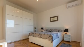 Ein Schlafzimmer mit Bett, Nachttischen, einem Kleiderschrank und einer Klimaanlage.