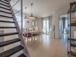 A modern interior with a staircase, dining area, and a view to the outside.
