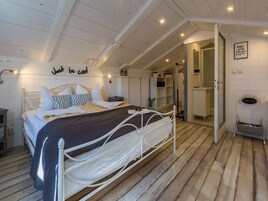 A bedroom with a bed, bedside tables, a wardrobe, and a bathroom visible through an open door.