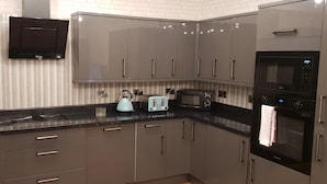 A modern kitchen with grey cabinets, a black countertop, a kettle, a toaster, and a microwave. - Manhattan 5 (Maidstone)