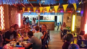 A restaurant with tables and chairs, a counter, and a few people dining.