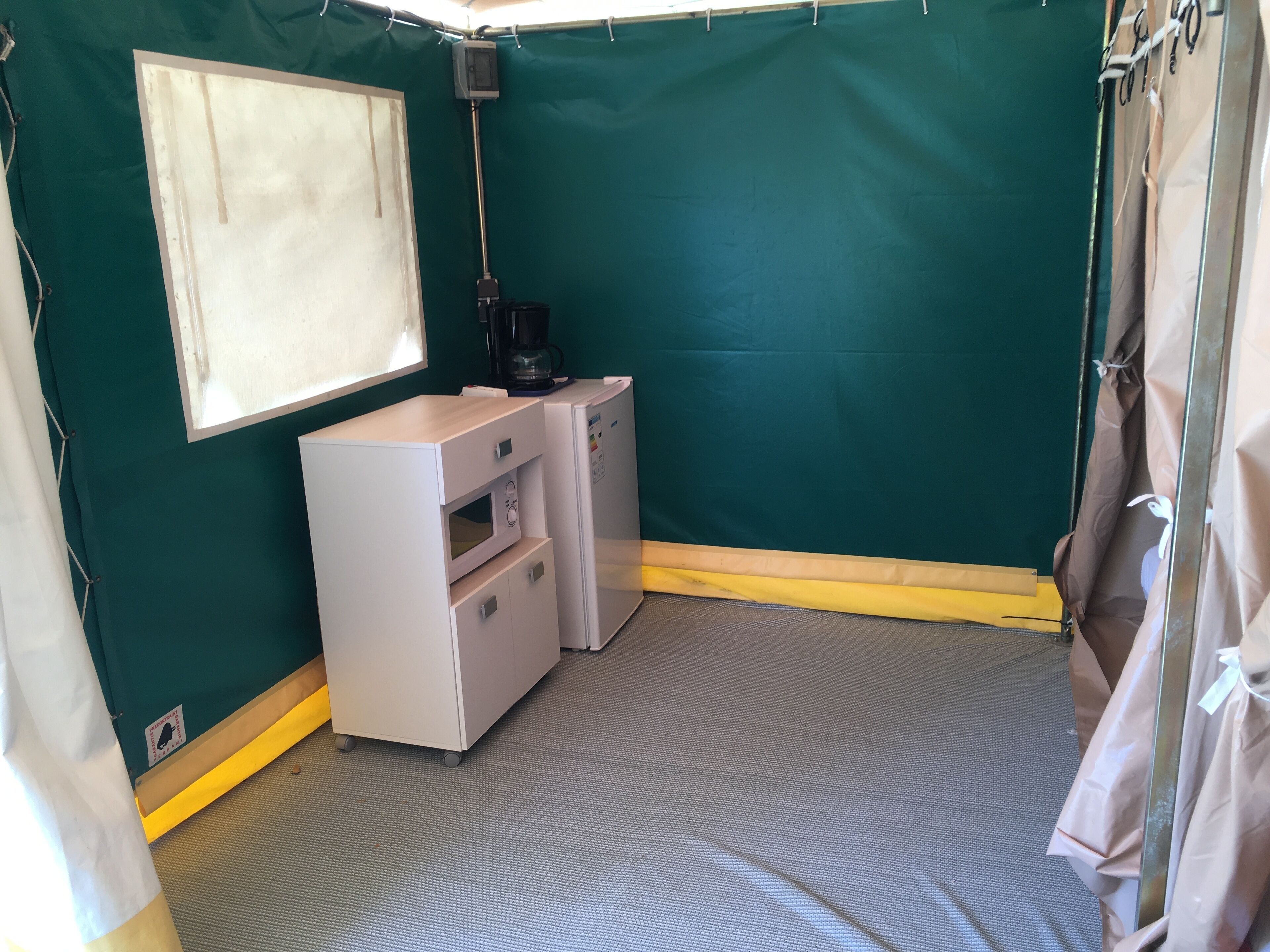 Una habitación compacta con kitchenette, una ventana pequeña y una estructura similar a una tienda de campaña.