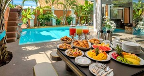A breakfast buffet with tropical fruit, pastries, and beverages by a poolside. - TUCHELAND Luxury Pool Villa Pattaya Walking Street (Pattaya)