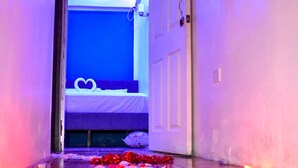 A hallway leading to a room with a bed, a heart-shaped decoration on the bed, and a string of lights along the ceiling. - The Hummingbird Villa Luxury Suite- Vacation Rental Beach Resort Villa in Mayaro (Guayaguayare)
