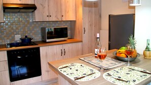 Een keuken met houten kastjes, een magnetron, een fornuis en een fruitschaal op het aanrecht.