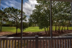 A view from a balcony with a railing, overlooking a grassy area with trees and a clear sky. - 522 Wedgewood - Barefoot Resort Rentals (North Myrtle Beach)