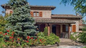 A two-story house with a stone facade, wooden shutters, and a tiled roof.