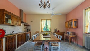 A kitchen with wooden cabinets, a dining table, chairs, a chandelier, and a ceiling fan.