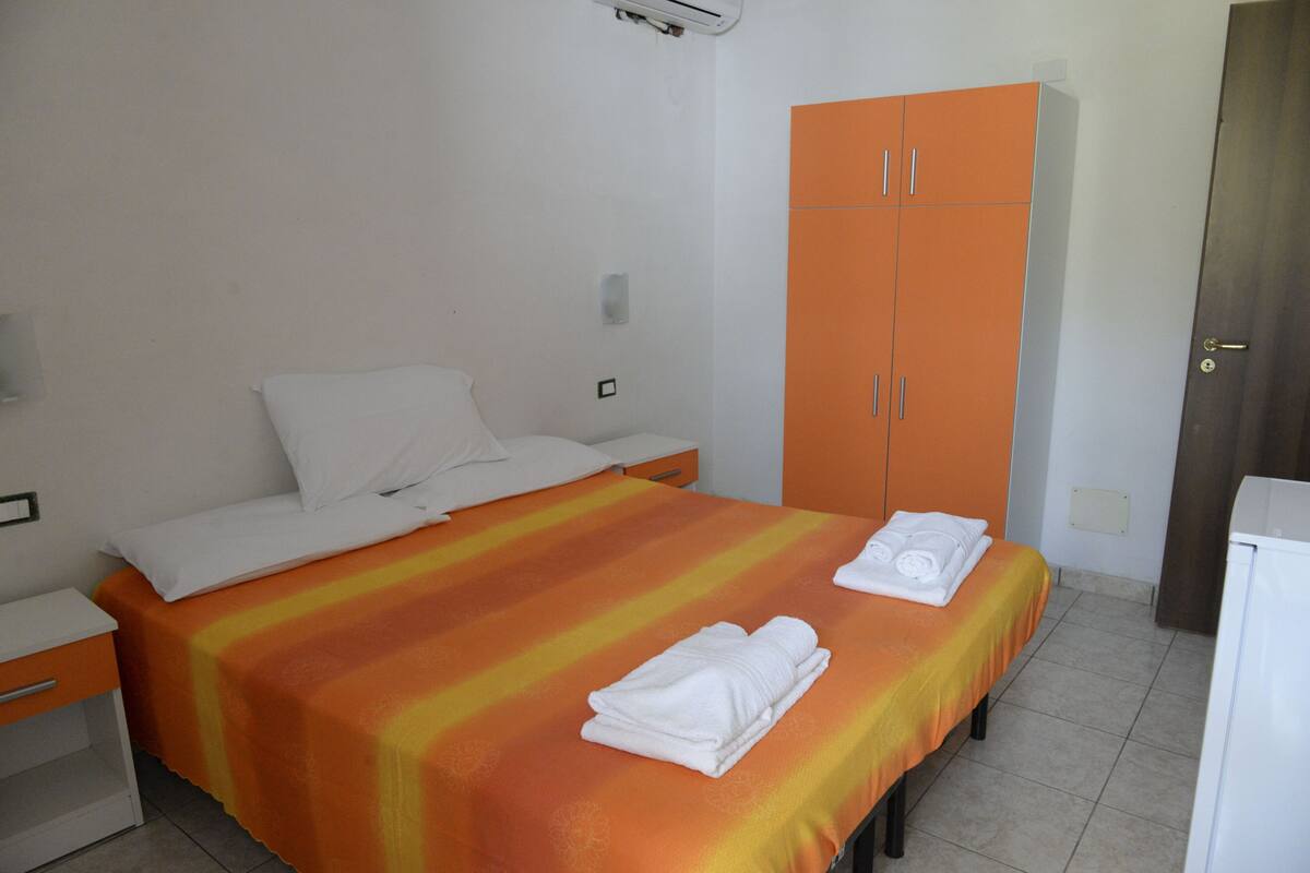 A hotel room with a bed, a wardrobe, a nightstand, and a bathroom.