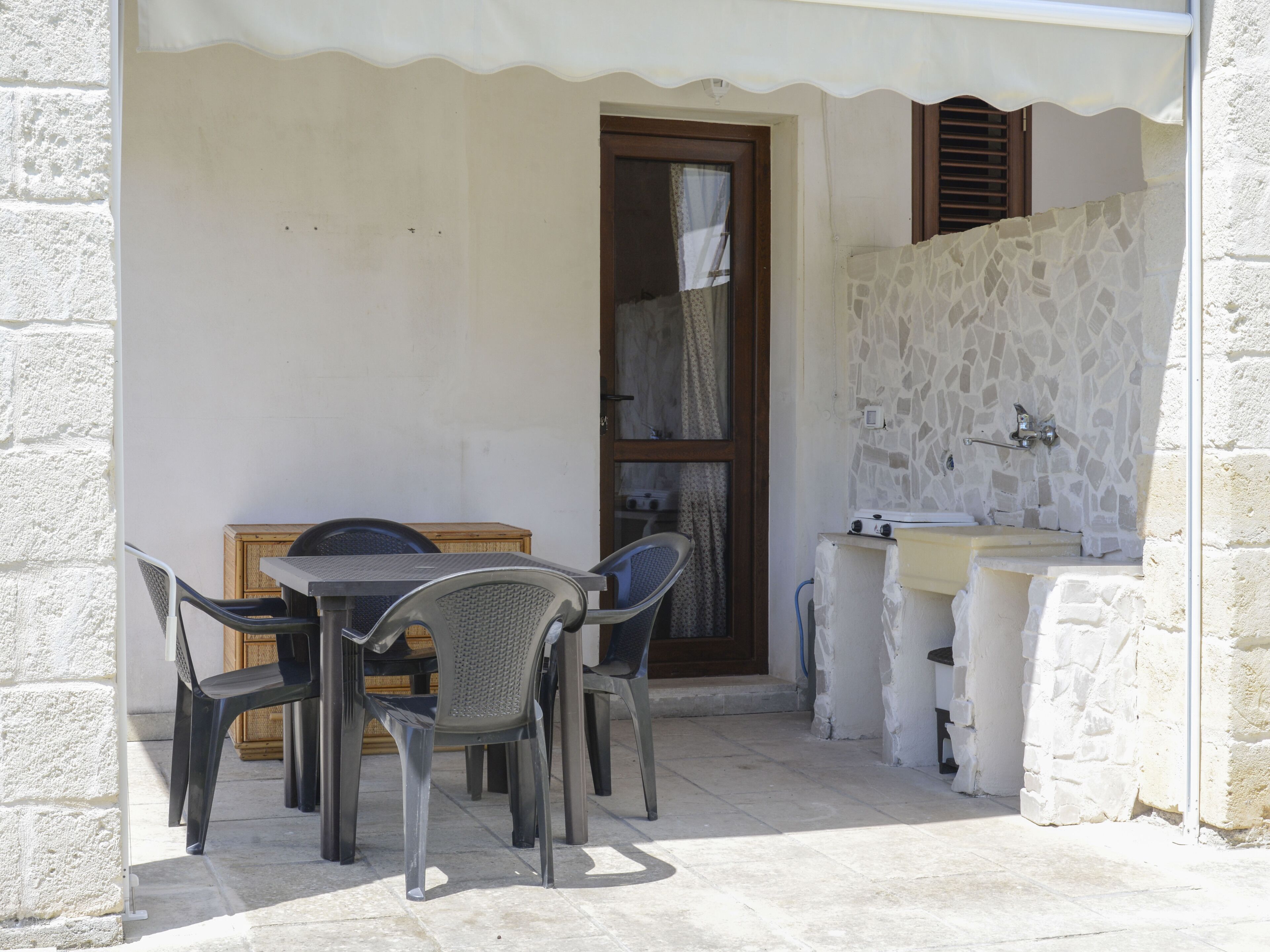 A patio with a table and chairs, a sink, and a stone wall.
