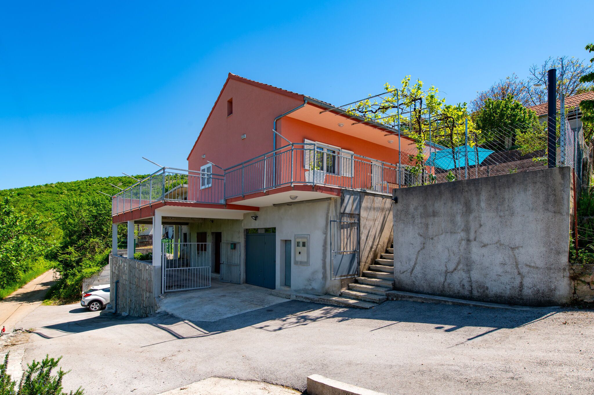 A two-story house with a balcony, a staircase, and a car parked in front.