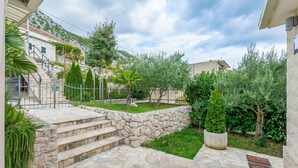A stone staircase leading to a stone wall, surrounded by greenery and a fence. - Villa Holiday Home Zvečanje (Zvecanje)