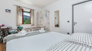 A hotel room with a bed, a chair, a desk, a window with curtains, a wardrobe, and a door. - Villa Holiday Home Zvečanje (Zvecanje)