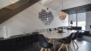 A modern dining area with a round table, black chairs, and a decorative ceiling light. - Stunning apartment in Rømø with house sea view (Rømø)