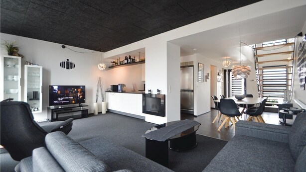 A modern living room with a grey sofa, a flat-screen TV, and a dining area with a table and chairs. - Stunning apartment in Rømø with house sea view (Rømø)